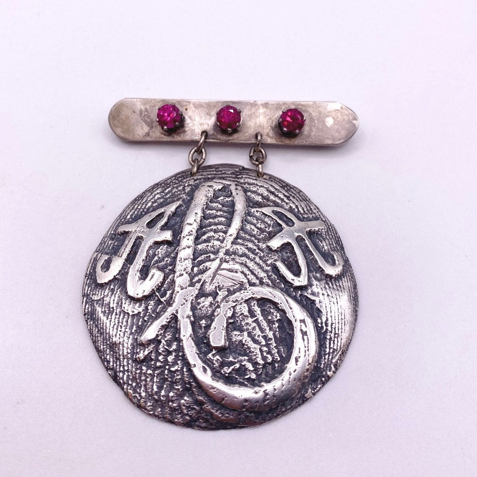 Vintage Metal Metal Anagram Design With Three Median Rubies 2” Round