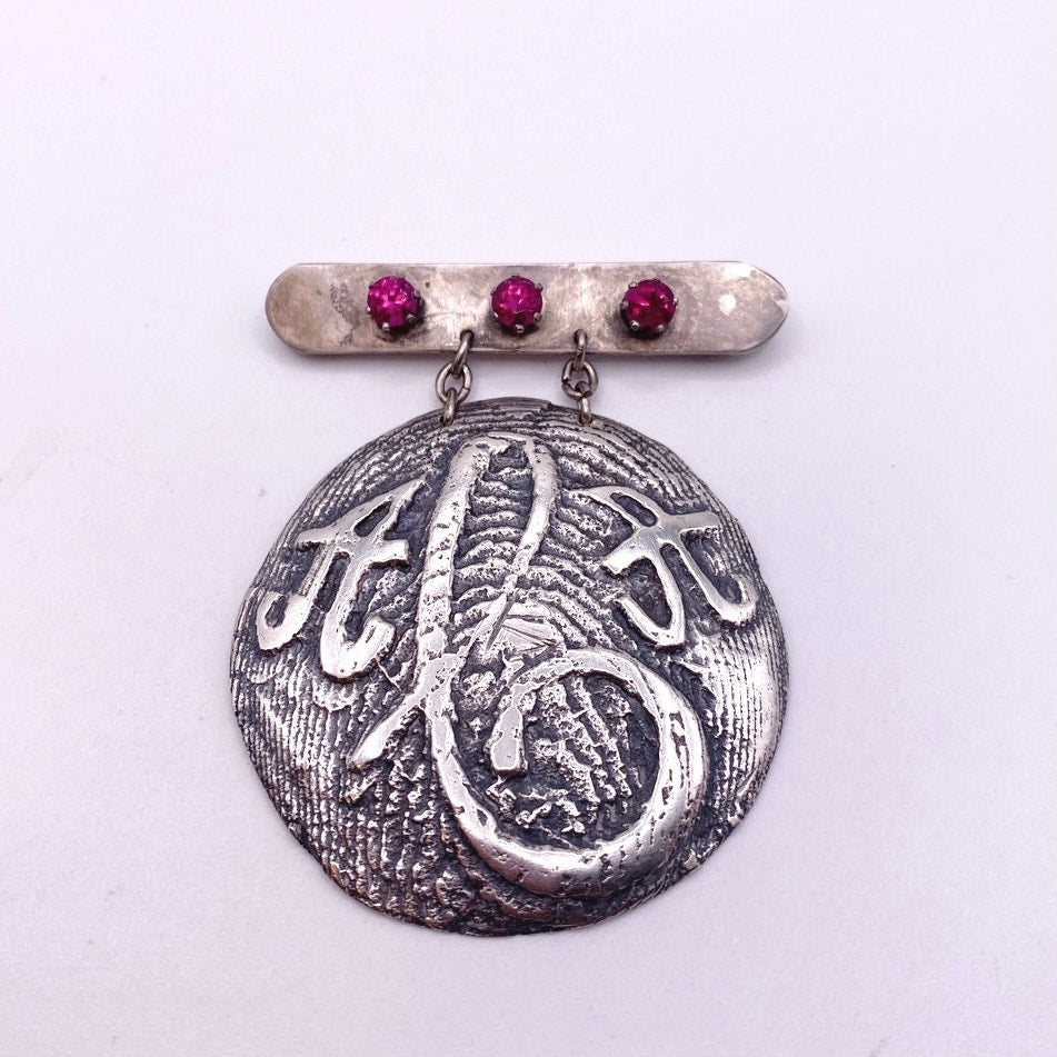Vintage Metal Metal Anagram Design With Three Median Rubies 2” Round