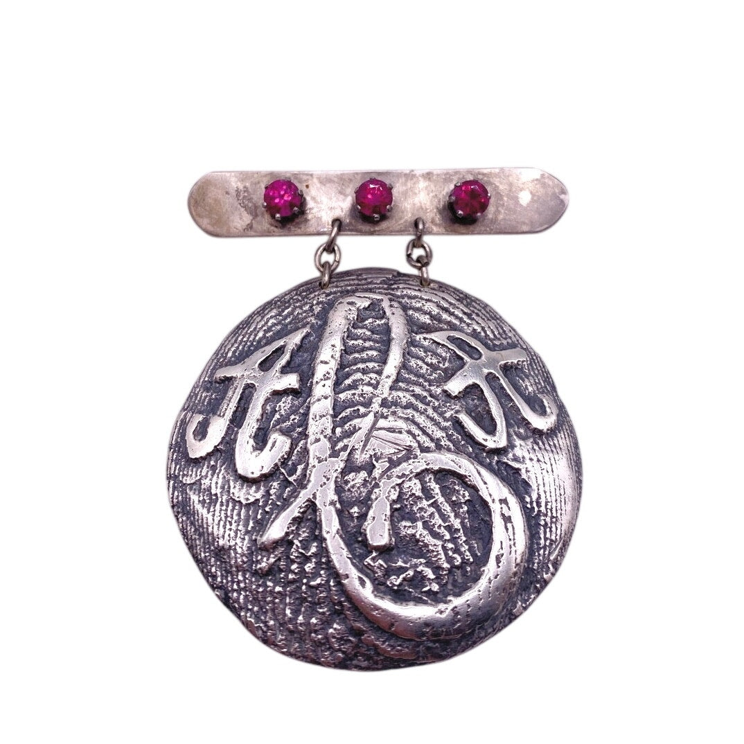 Vintage Metal Metal Anagram Design With Three Median Rubies 2” Round