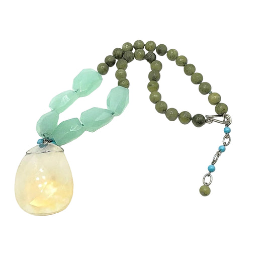 Necklace with green beads and a large yellow pendant on a white background